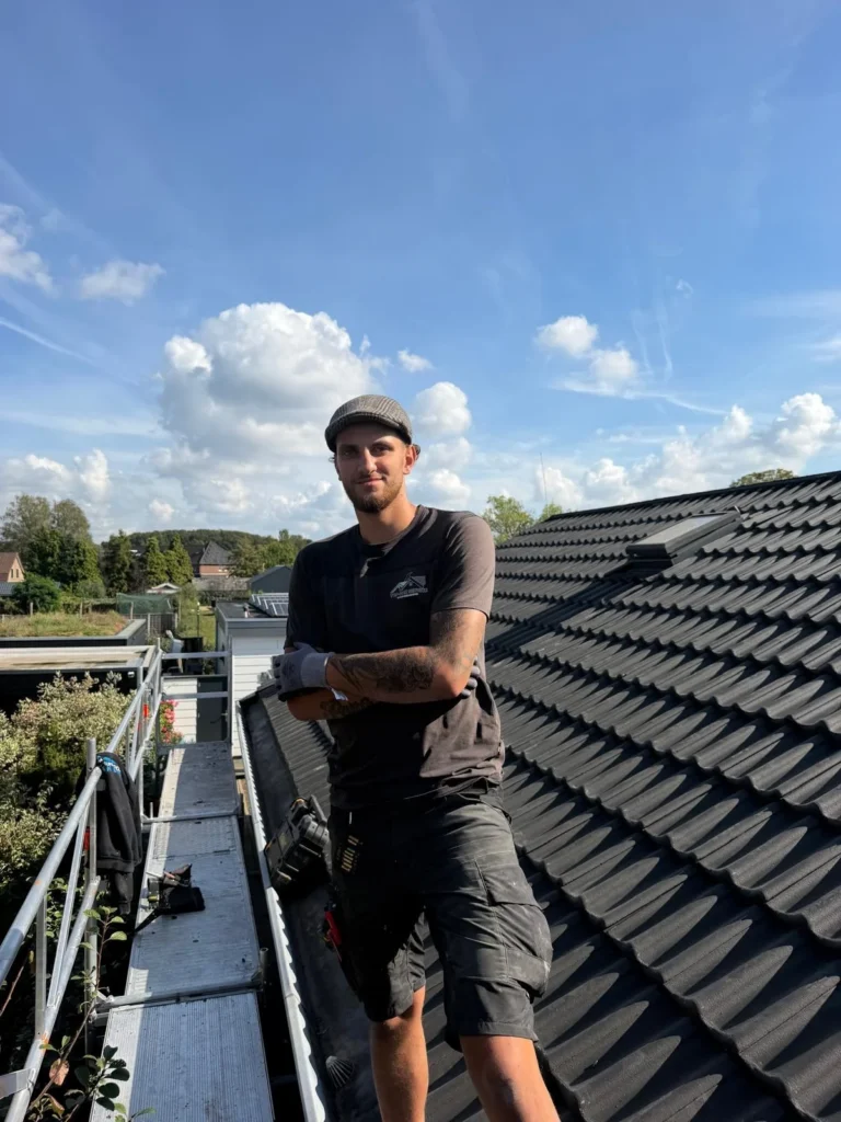 Roofer poses on the scaffolding next to a new tiled roof in Ede.
