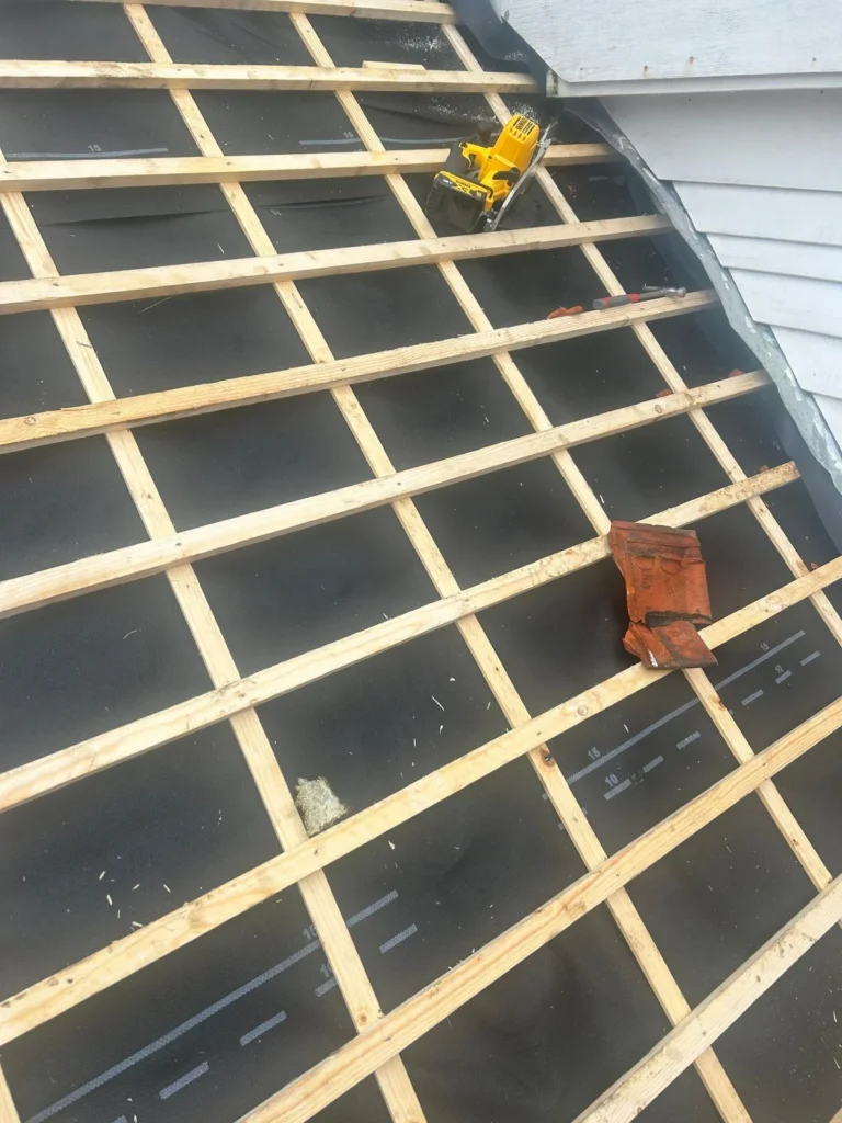New battens on foil with an old roof tile and circular saw in Renkum