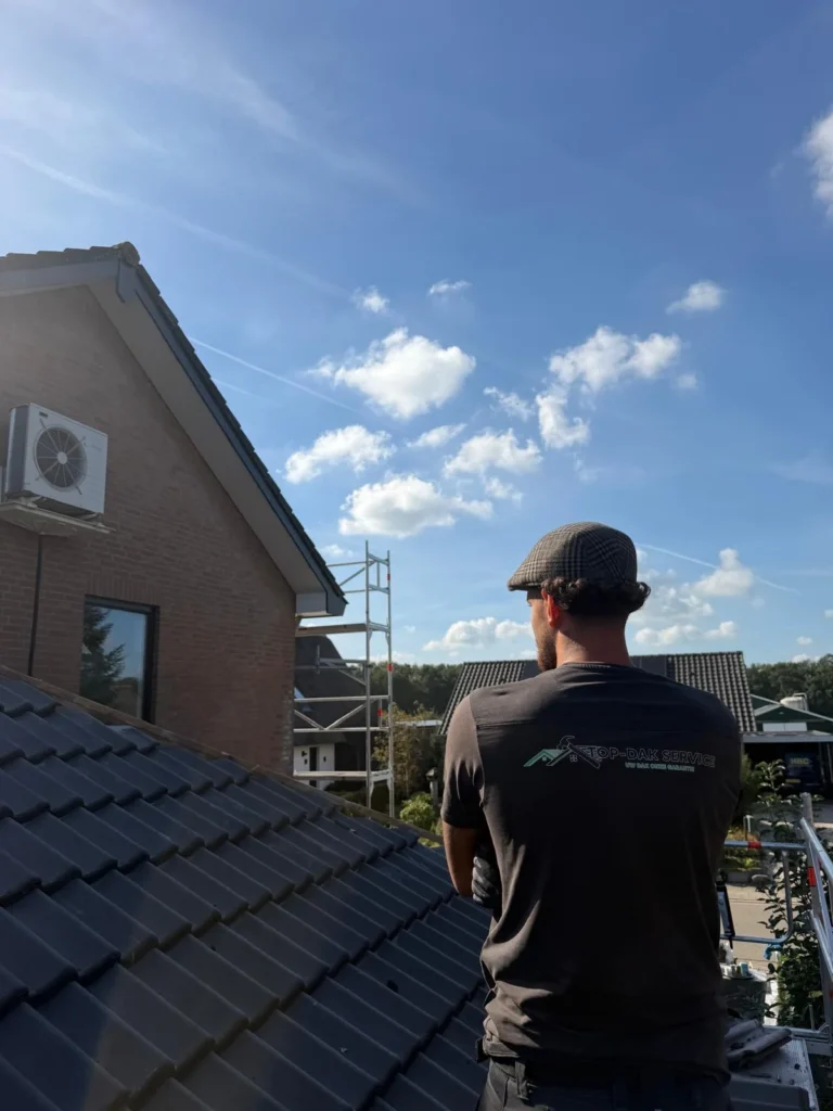 Dakdekker staat op de steiger en kijkt over het pannendak in Ede