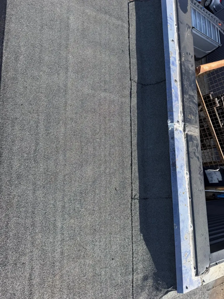 Nieuwe bitumen dakbedekking langs de dakrand van een bedrijfshal in Amersfoort door Dakdekker Specialist Ede