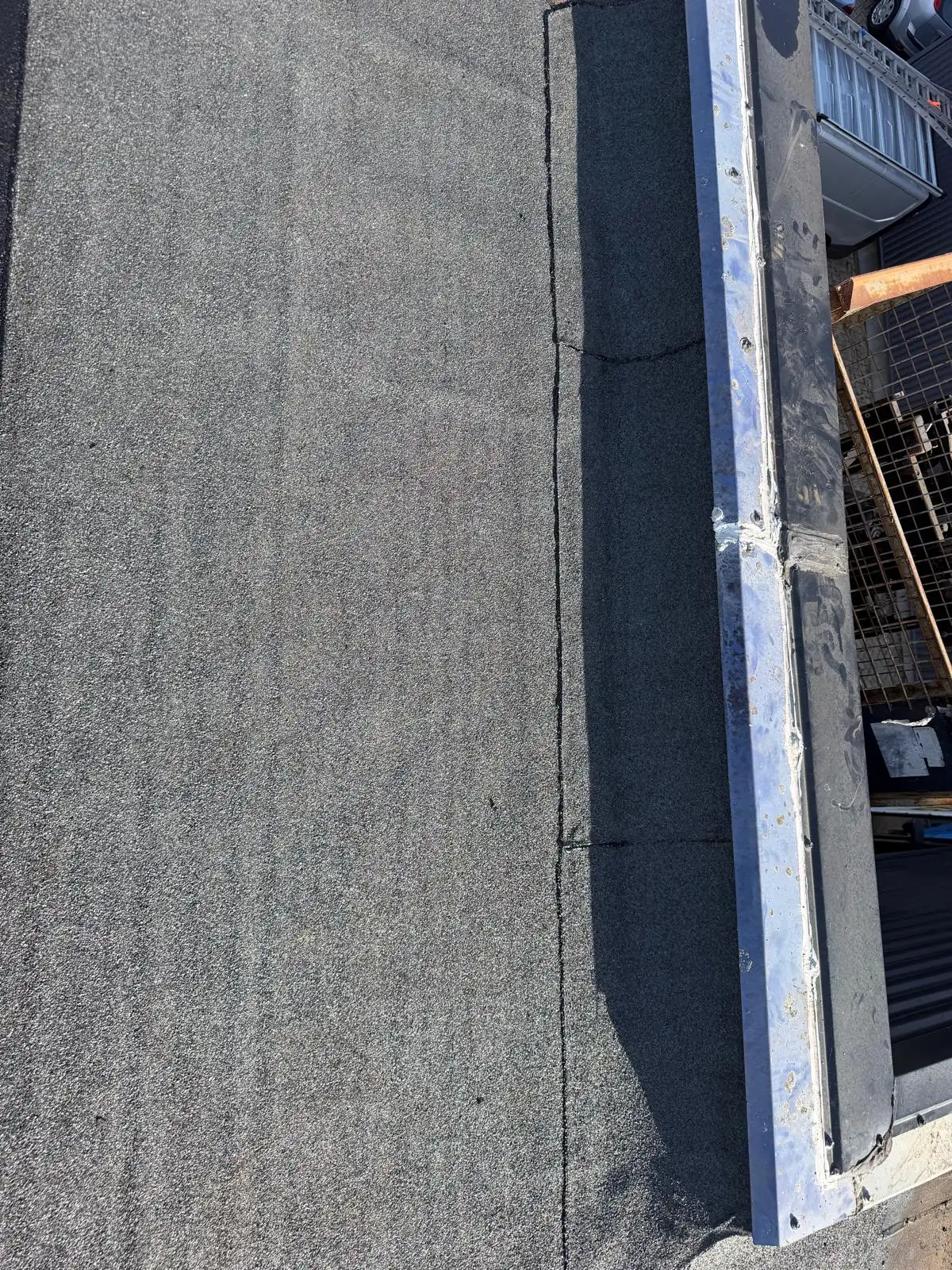 Nieuwe bitumen dakbedekking langs de dakrand van een bedrijfshal in Amersfoort door Dakdekker Specialist Ede