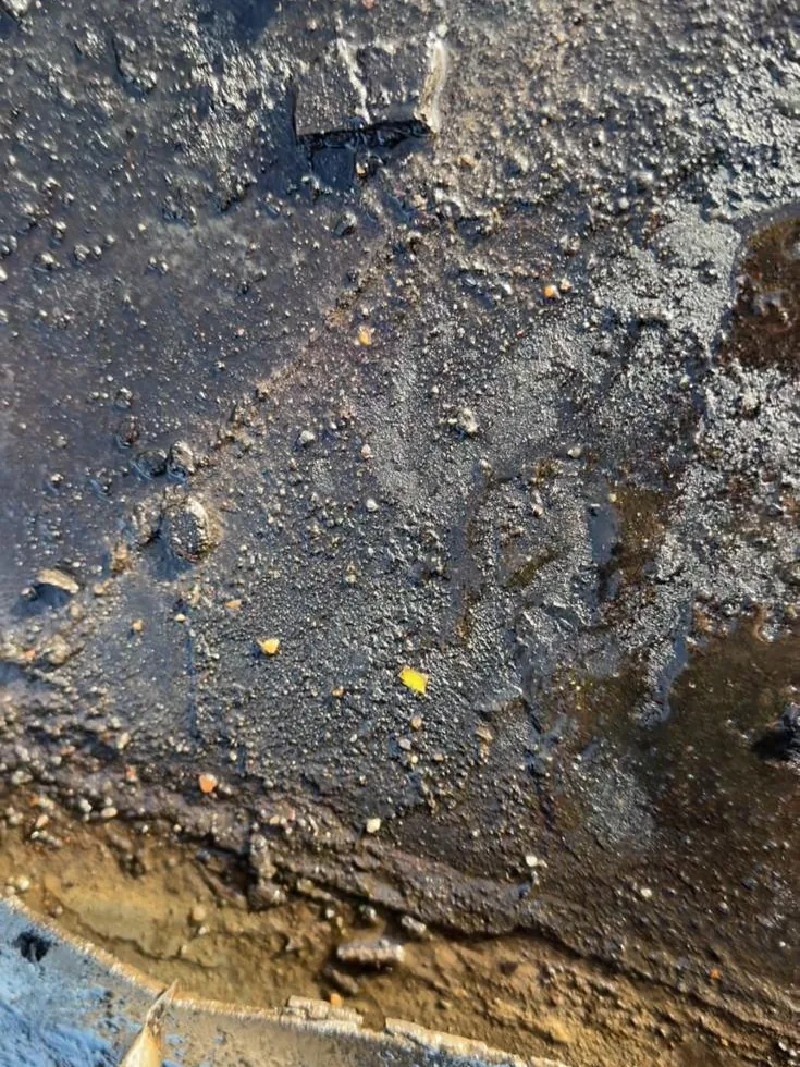 Water onder de oude bitumen dakbedekking van een bedrijfshal in Amersfoort na het openmaken