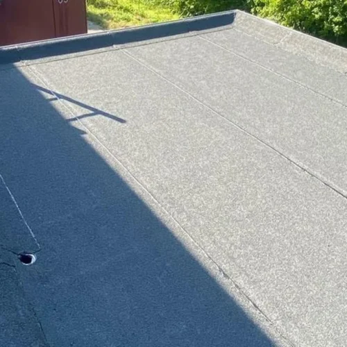 Afgewerkt bitumen plat dak op een aanbouw met strakke dakrand in Ede